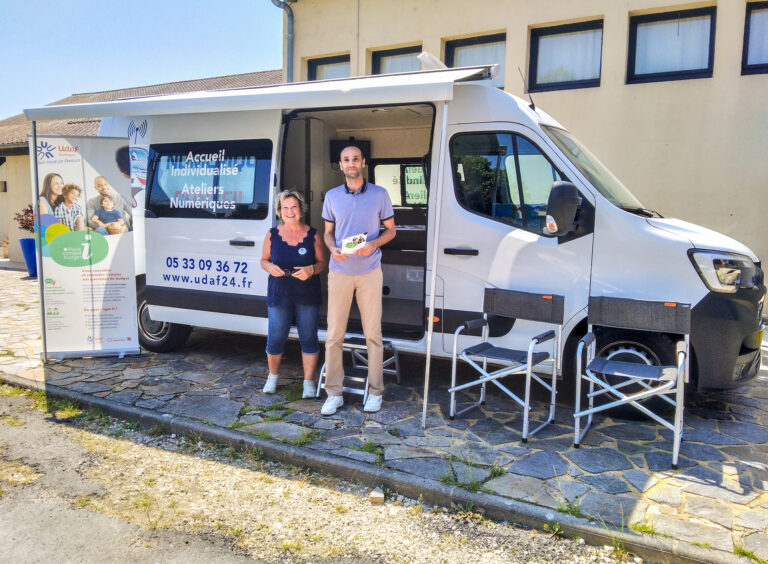 Conseiller numérique avec une personne devant le Connect'e-bus au Forum pour l'emploi utile