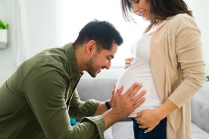 un père qui touche le ventre de sa femme enceinte